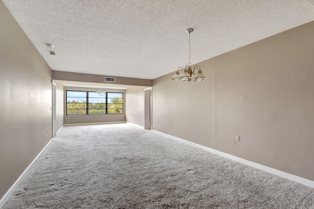 carpeted spare room featuring a textured ceiling and a notable chandelier