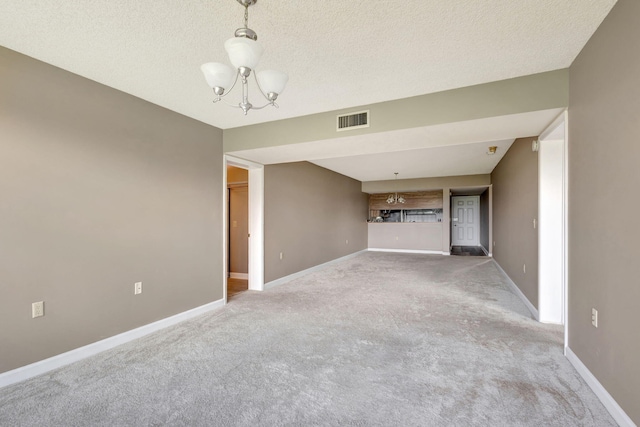 unfurnished living room with a textured ceiling, light colored carpet, and a chandelier