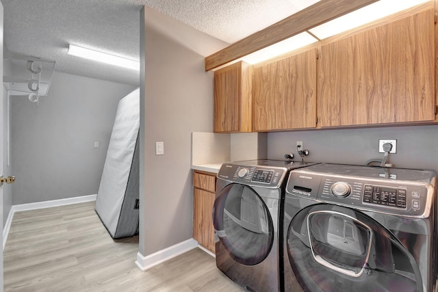 washroom with light wood-type flooring, cabinets, independent washer and dryer, and a textured ceiling