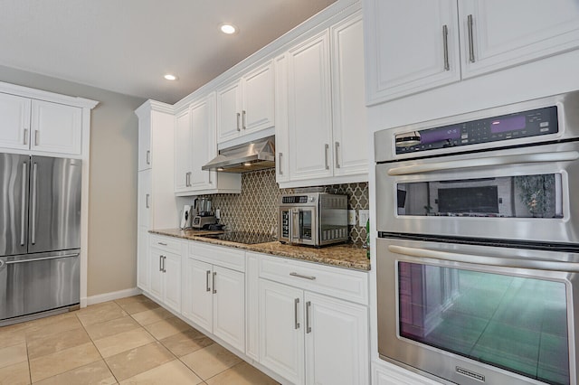 kitchen featuring stainless steel appliances, white cabinetry, and dark stone counters