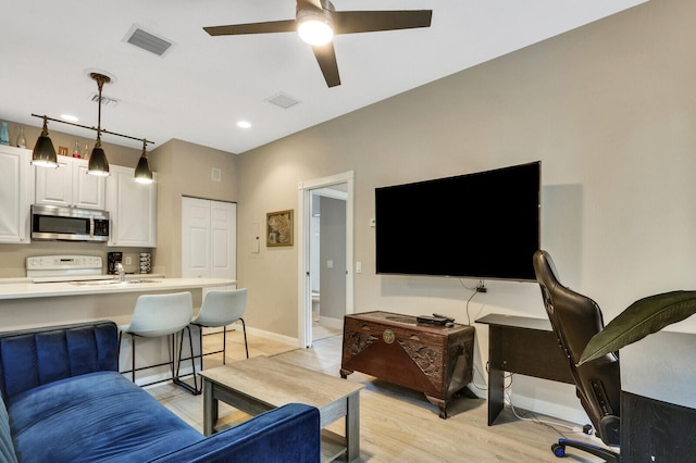 living room featuring ceiling fan and light wood-type flooring