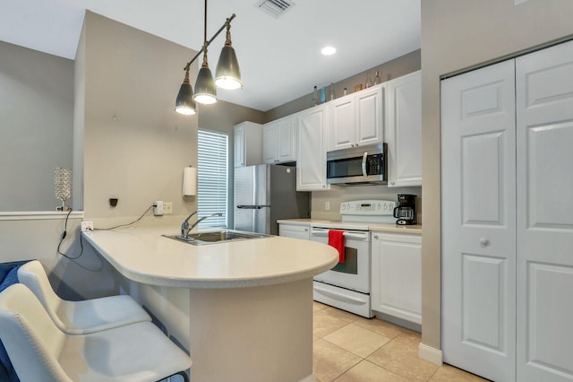 kitchen with kitchen peninsula, appliances with stainless steel finishes, a kitchen breakfast bar, white cabinets, and pendant lighting