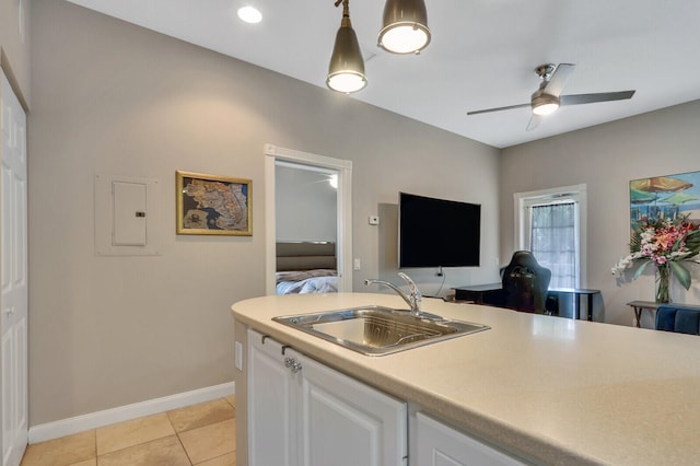 kitchen with electric panel, sink, ceiling fan, white cabinetry, and decorative light fixtures