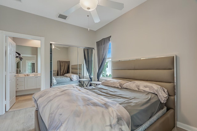 bedroom with ensuite bathroom, ceiling fan, a closet, and light wood-type flooring