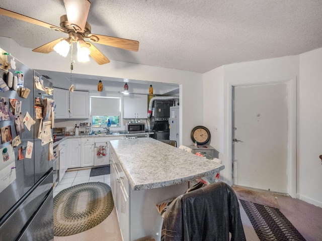 kitchen featuring white cabinets, appliances with stainless steel finishes, a textured ceiling, and a kitchen island