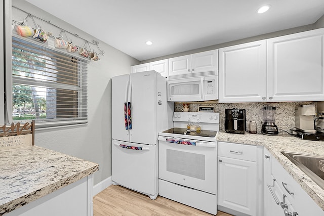 kitchen with tasteful backsplash, white appliances, light hardwood / wood-style floors, and white cabinets