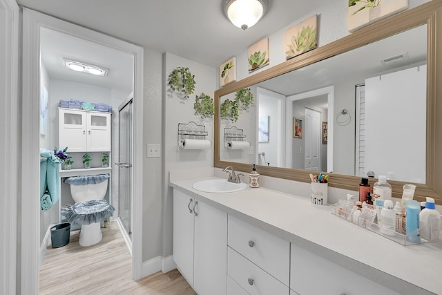 bathroom featuring wood-type flooring, vanity, and a shower with shower door