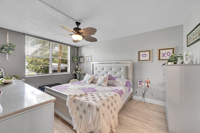 bedroom with a textured ceiling, ceiling fan, and light hardwood / wood-style flooring