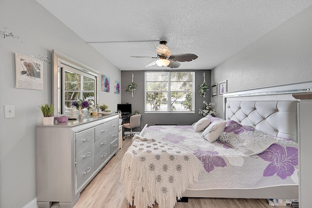 bedroom with light hardwood / wood-style floors, multiple windows, a textured ceiling, and ceiling fan