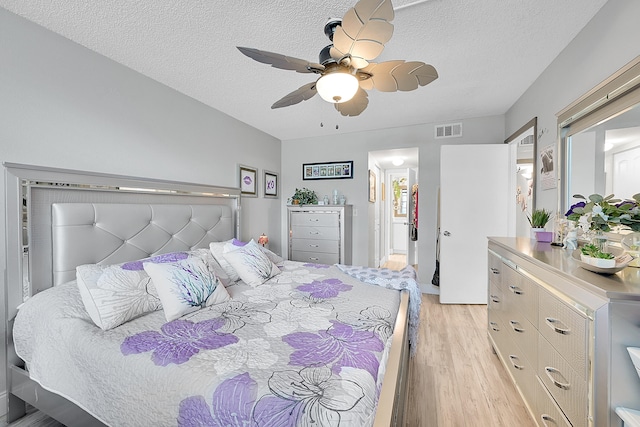 bedroom with ceiling fan, a textured ceiling, and light wood-type flooring