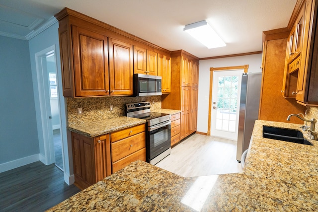 kitchen featuring crown molding, backsplash, appliances with stainless steel finishes, sink, and light hardwood / wood-style floors