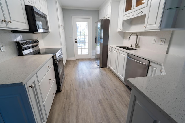 kitchen with sink, white cabinets, stainless steel appliances, light stone countertops, and light wood-type flooring