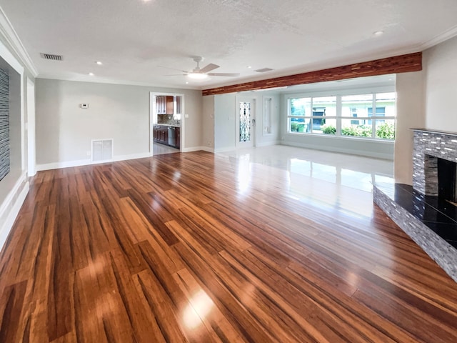 unfurnished living room featuring hardwood / wood-style flooring, ceiling fan, a textured ceiling, a fireplace, and crown molding