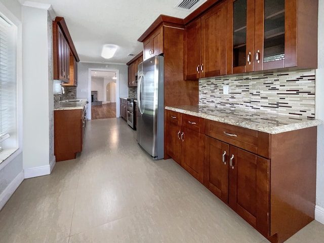 232 NW 25th St, Wilton Manors, FL 33311 - kitchen featuring stainless steel appliances, baseboards, decorative backsplash, arched walkways, and light stone counters
