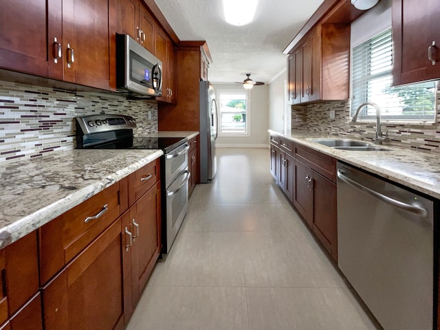 kitchen featuring light stone counters, appliances with stainless steel finishes, decorative backsplash, sink, and ceiling fan