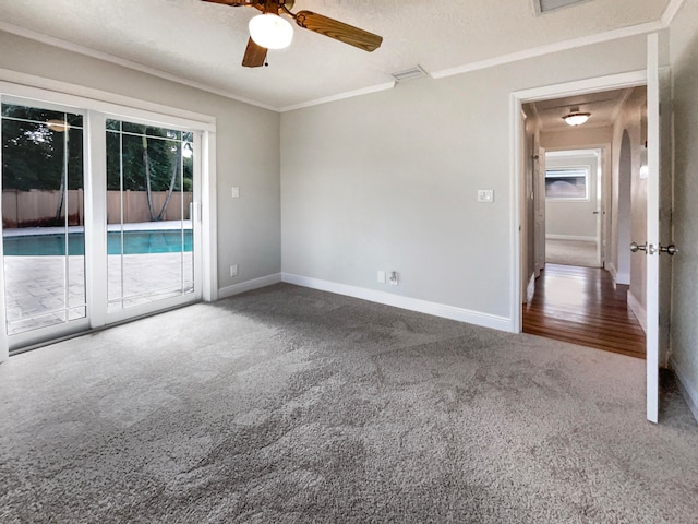 carpeted empty room featuring ceiling fan, a textured ceiling, crown molding, and plenty of natural light