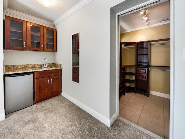 kitchen with light carpet, sink, ornamental molding, stainless steel dishwasher, and light stone countertops