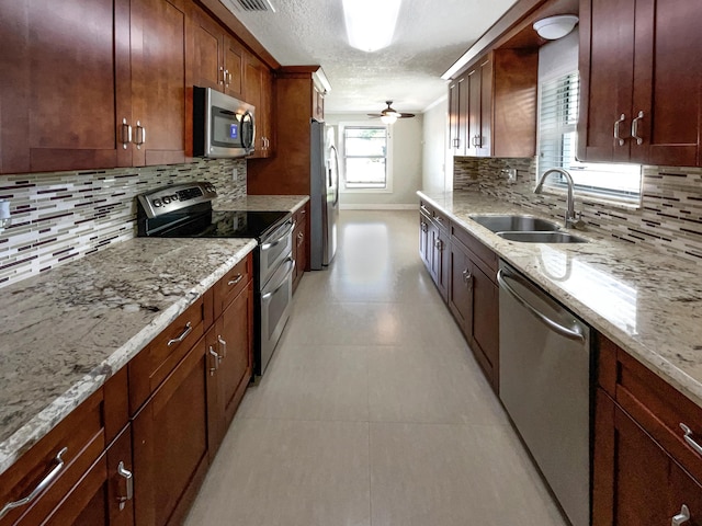232 NW 25th St, Wilton Manors, FL 33311 - kitchen with stainless steel appliances, a sink, backsplash, a textured ceiling, and light stone countertops