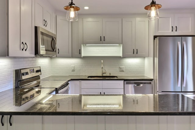 kitchen featuring white cabinets, hanging light fixtures, appliances with stainless steel finishes, and tasteful backsplash