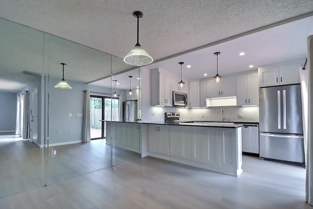 kitchen featuring decorative light fixtures, white cabinetry, a textured ceiling, and appliances with stainless steel finishes