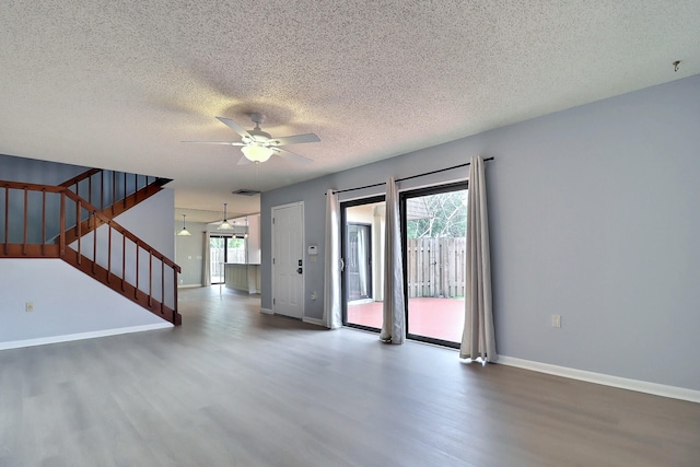 empty room with ceiling fan, a healthy amount of sunlight, a textured ceiling, and hardwood / wood-style flooring