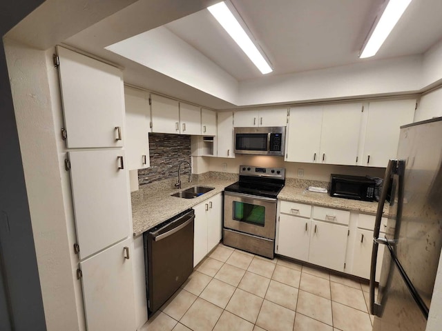 kitchen featuring white cabinets, black appliances, sink, tasteful backsplash, and light tile patterned flooring