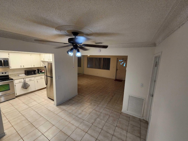 kitchen with light tile patterned flooring, appliances with stainless steel finishes, ceiling fan, a textured ceiling, and white cabinets