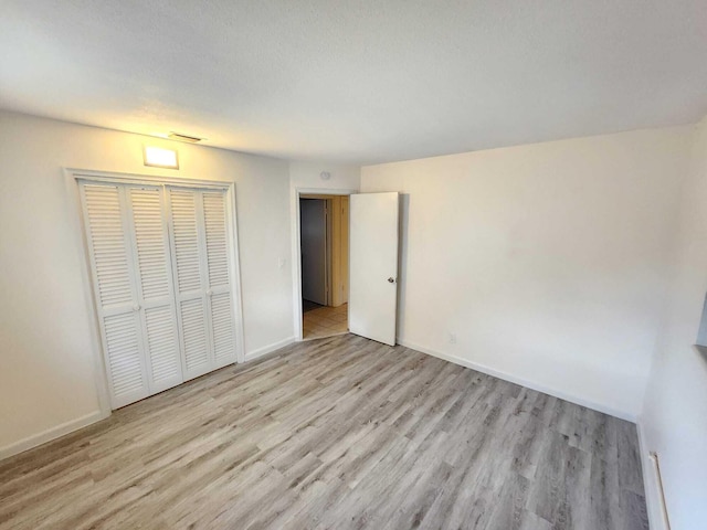 unfurnished bedroom featuring light wood-type flooring and a closet