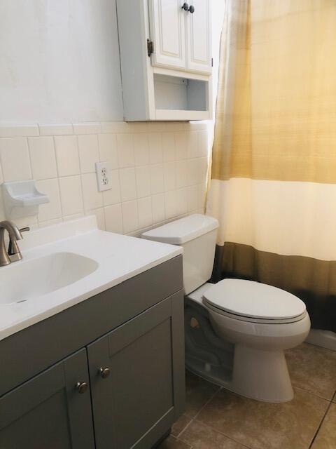 2727-29 NE 30th Ave, Lighthouse Point, FL 33064 - bathroom with vanity, tile patterned flooring, a shower with shower curtain, tile walls, and backsplash