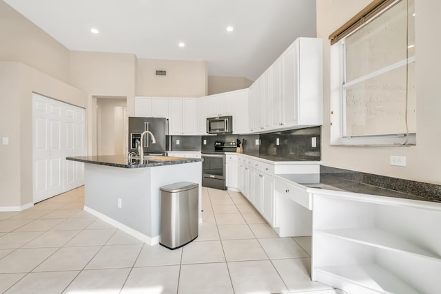 kitchen with appliances with stainless steel finishes, sink, light tile patterned floors, white cabinetry, and an island with sink