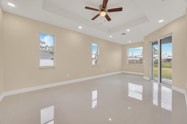 tiled spare room featuring ceiling fan and a raised ceiling