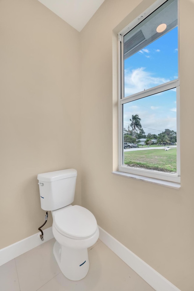 bathroom with toilet, tile patterned flooring, and plenty of natural light