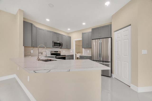 kitchen featuring kitchen peninsula, appliances with stainless steel finishes, sink, and gray cabinetry