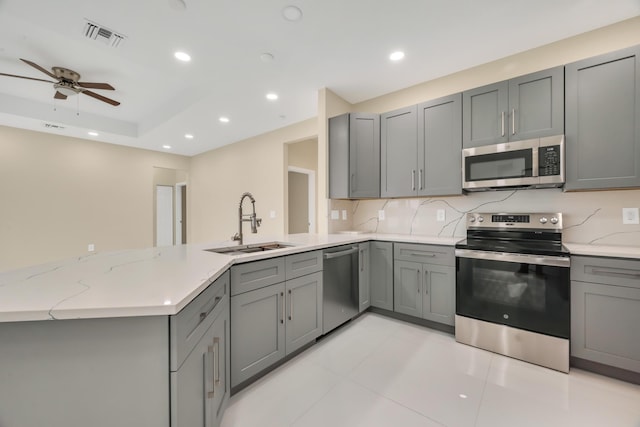 kitchen featuring stainless steel appliances, gray cabinetry, kitchen peninsula, and sink