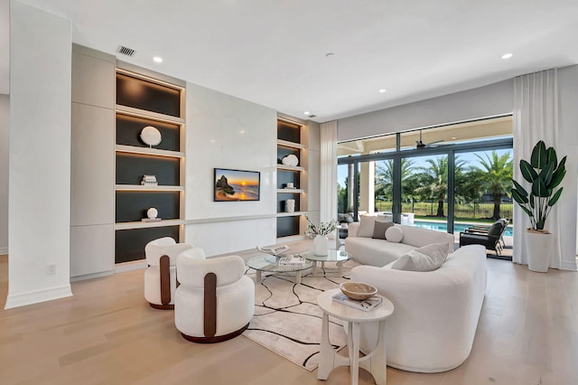 living room with built in shelves and light hardwood / wood-style flooring