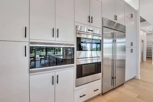 kitchen with white cabinets, appliances with stainless steel finishes, and light hardwood / wood-style floors