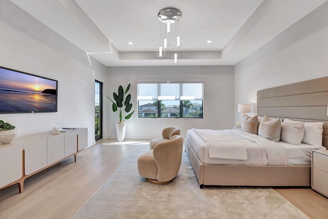 bedroom with a raised ceiling and light hardwood / wood-style flooring