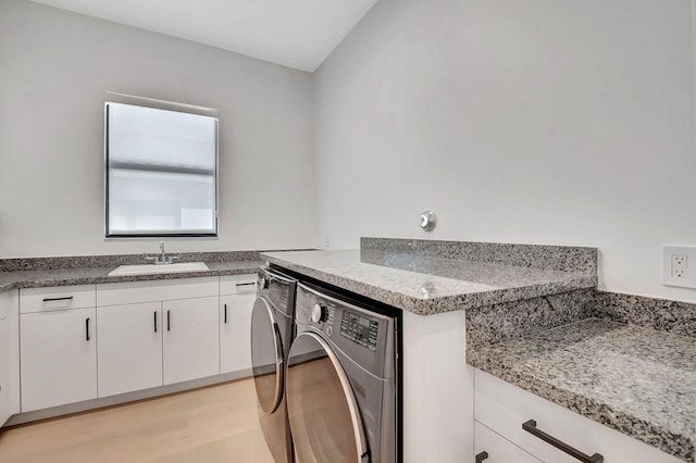 washroom with washer and dryer, light wood-type flooring, cabinets, and sink