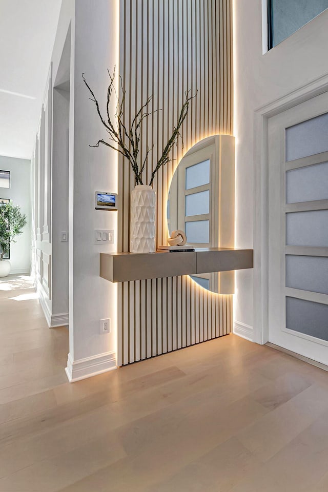 hallway featuring built in shelves, a towering ceiling, and wood-type flooring