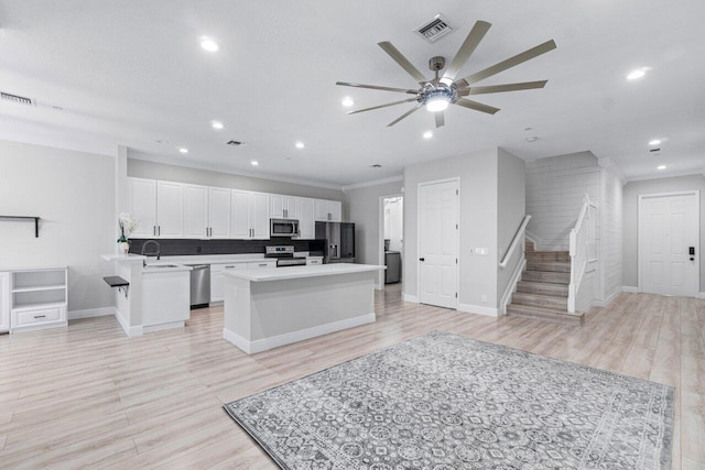 kitchen featuring sink, white cabinets, light hardwood / wood-style floors, a kitchen island, and appliances with stainless steel finishes