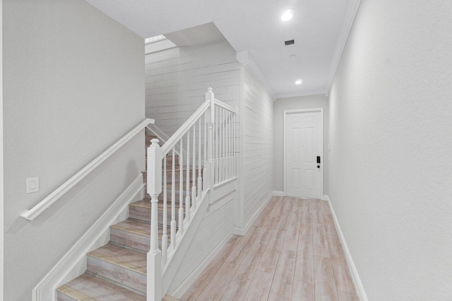 stairway with hardwood / wood-style flooring and ornamental molding