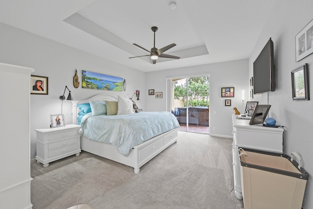 carpeted bedroom with ceiling fan, a raised ceiling, and access to outside