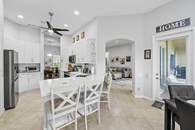 kitchen featuring kitchen peninsula, tasteful backsplash, decorative light fixtures, white cabinetry, and stainless steel appliances