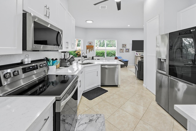 kitchen featuring light stone countertops, sink, stainless steel appliances, light tile patterned floors, and white cabinets