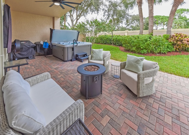 view of patio / terrace with ceiling fan, area for grilling, a hot tub, and an outdoor living space with a fire pit