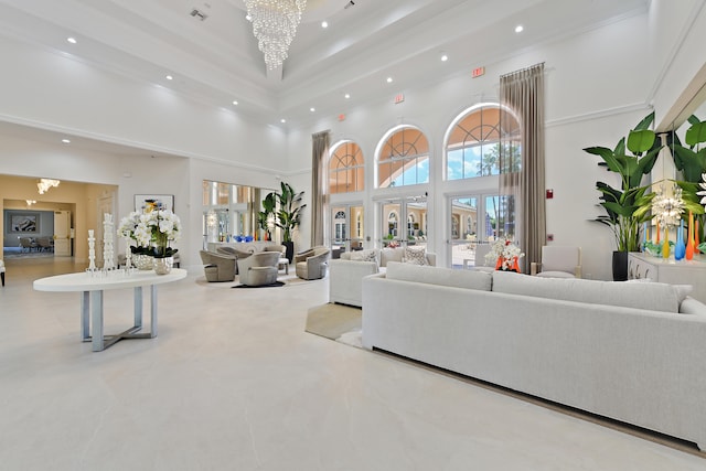 living room featuring ornamental molding, a towering ceiling, and a notable chandelier