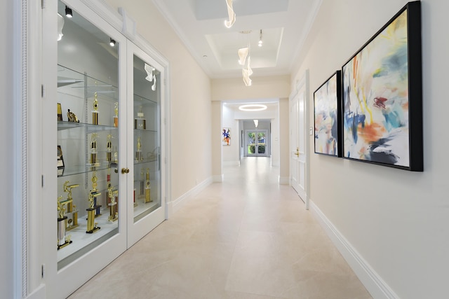 corridor with a tray ceiling, crown molding, and french doors