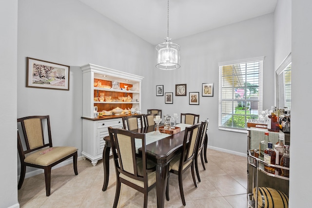 dining space featuring light tile patterned floors, a towering ceiling, and a chandelier