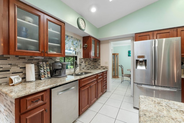 kitchen featuring lofted ceiling, sink, decorative backsplash, light stone countertops, and appliances with stainless steel finishes