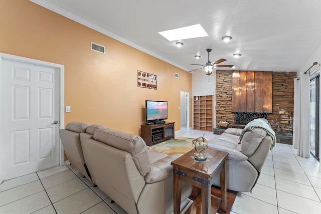 tiled living room featuring ceiling fan, ornamental molding, and vaulted ceiling with skylight